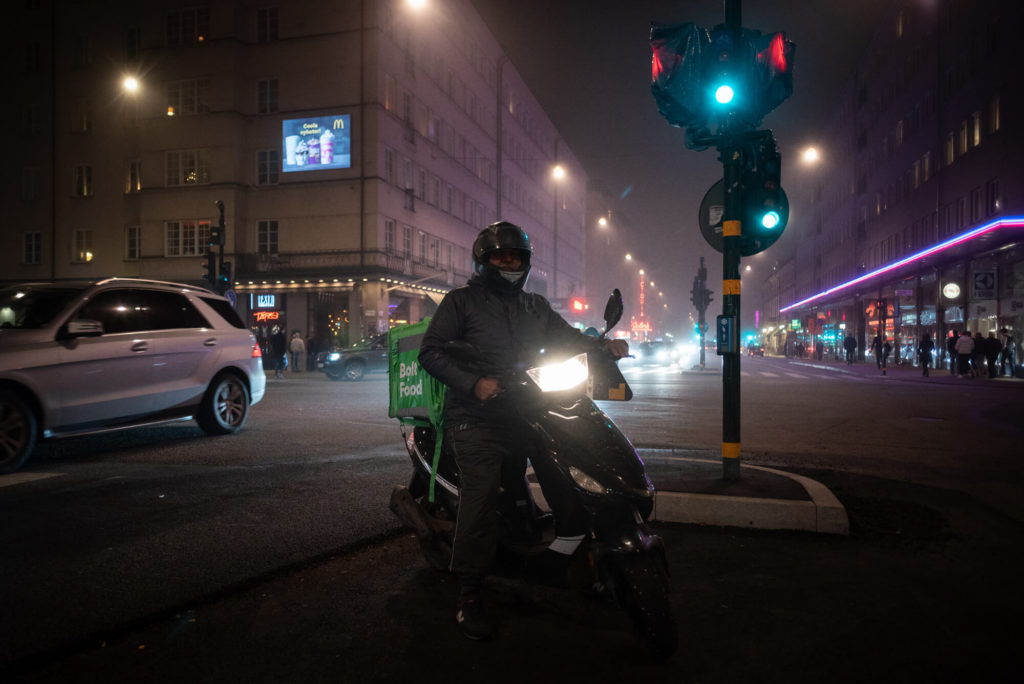 En matkurir på moped åker på vägen.