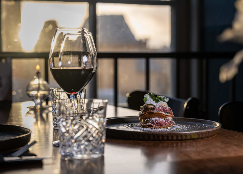 Två vinglas med rött vin och en tallrik med en välrepresenterad maträtt.