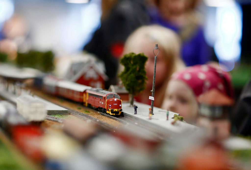 Två barn tittar på ett litet modeltåg som åker förbi dem.